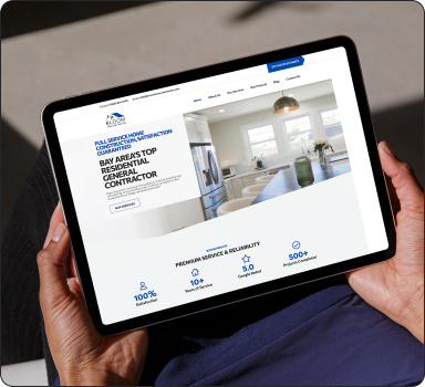 Hands holding a tablet showing a residential general contractor website, with a kitchen remodel hero image and trust badges for years of service, reviews and projects completed